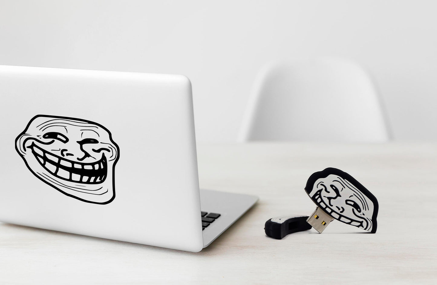 Troll face USB flash drive with metal USB plug on a desk near a laptop