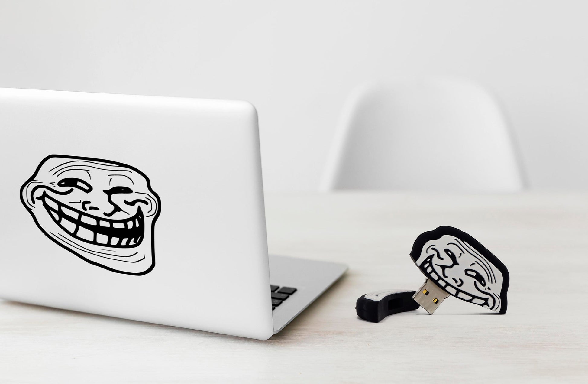 Troll face USB flash drive with metal USB plug on a desk near a laptop